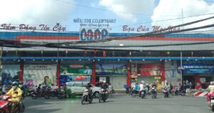 越南胡志明市Cống Quỳnh街上的Co.opmart超市外景，门前道路上摩托车与汽车川流不息，建筑外墙挂有越南文广告标语及品牌标识